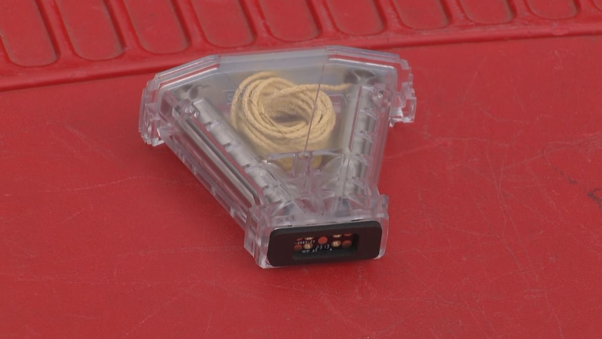 A coil of thin rope inside a plastic case is displayed on a red cloth.