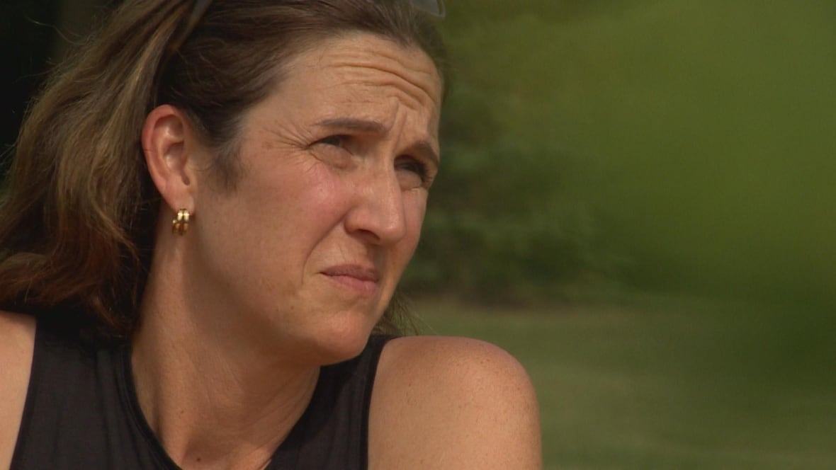 A woman in a black top looks to the side.