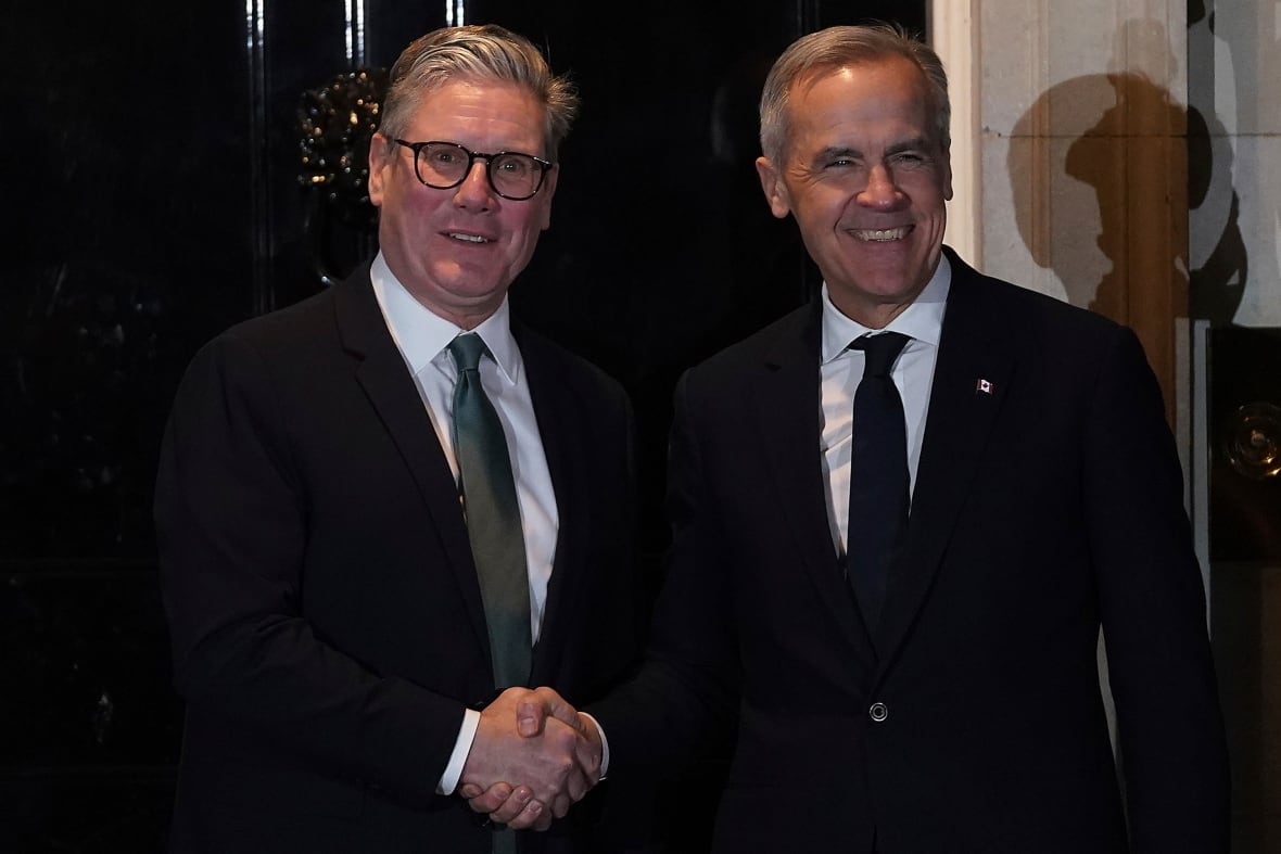 Two men shake hands in front of a doorway.