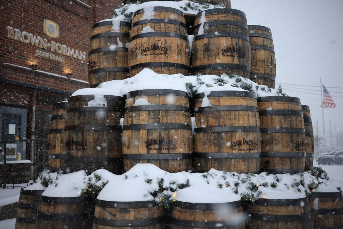 A stack of snow-covered whiskey barrels are shown.