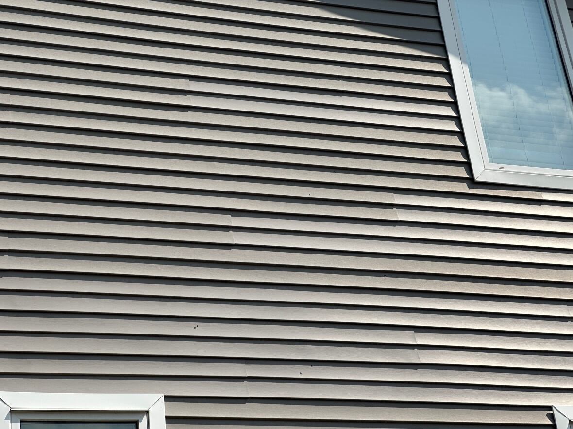 a siding of a house on Edgar Street with bullet holes.