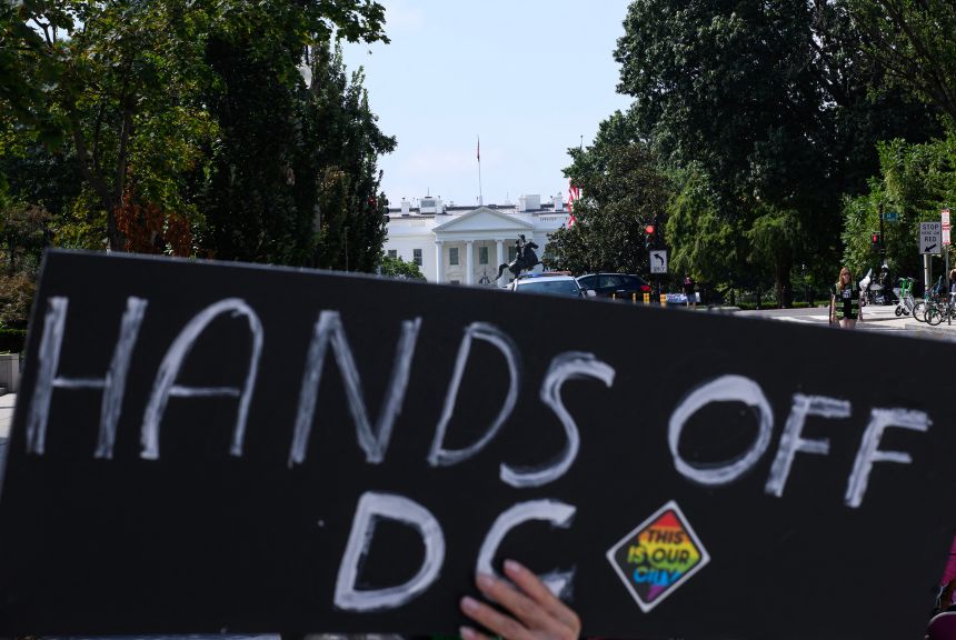 A protestor holds a placard as local residents rally against President Donald Trump's plans to activiate federal law enforcement in Washington, DC, on August 11.