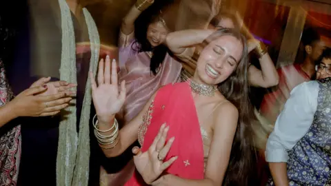 Third Place Young women, wearing colourful Indian outfits, dance at a party