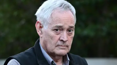 EPA Ian Wilkinson wearing a dress shirt and a black vest