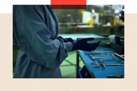 Bloomberg via Getty Images A surgeon puts on a pair of gloves while standing in front a table on which surgical instruments have been laid