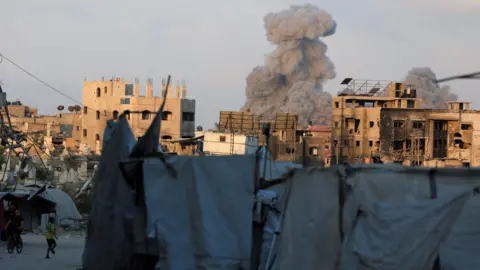 Reuters Smoke rises above buildings that are partially constructed and others that are burnt out and damaged, following an Israeli strike in Gaza City (21 August 2025)