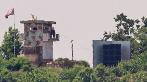 AFP via Getty Images North Korean soldier standing guard in a watch tower next to a giant loudspeaker near the Demilitarized Zone in Paju on 12 June 2025