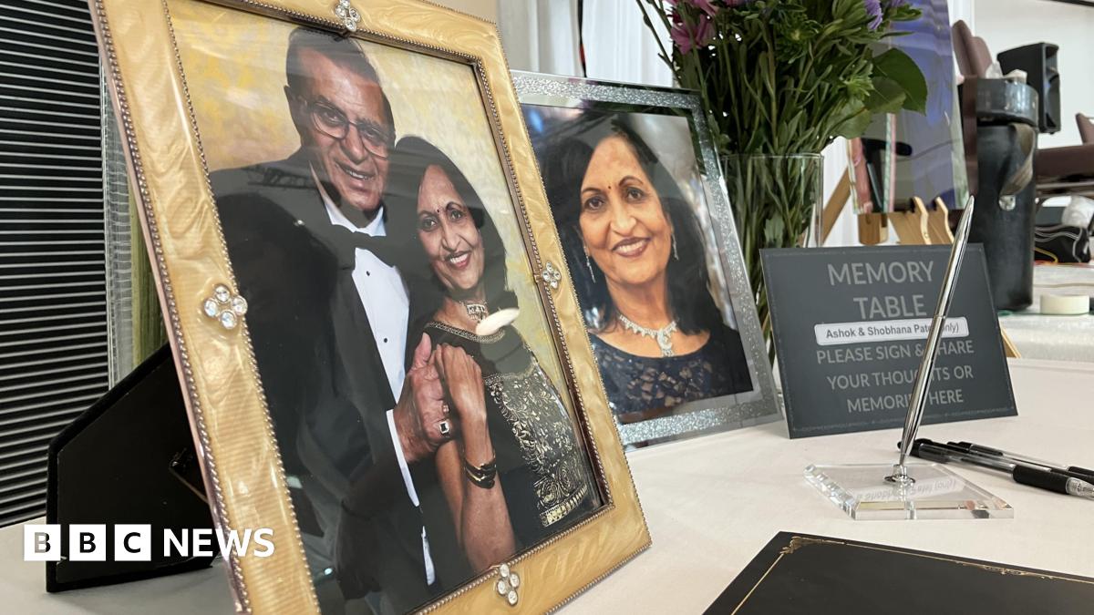 A table with framed photographs of Ashok and Shobhana Patel. There is also a sign that reads: "Memory Table. Please sign and share your thoughts or memories here". Next to it is a black book and three pens.