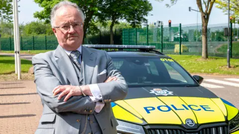 Police and Crime Commissioner for Leicestershire Rupert Matthews pictured in front of a police car