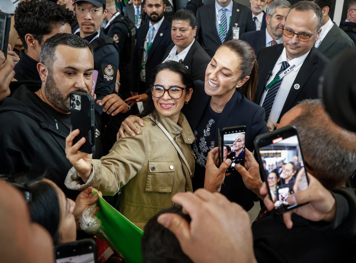 A woman poses for selfies in a crowd surrounding her.