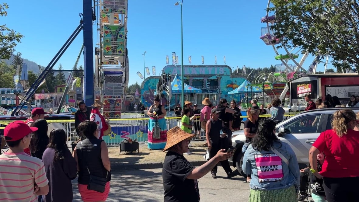 People gather and hold a fire outside a fair ride.
