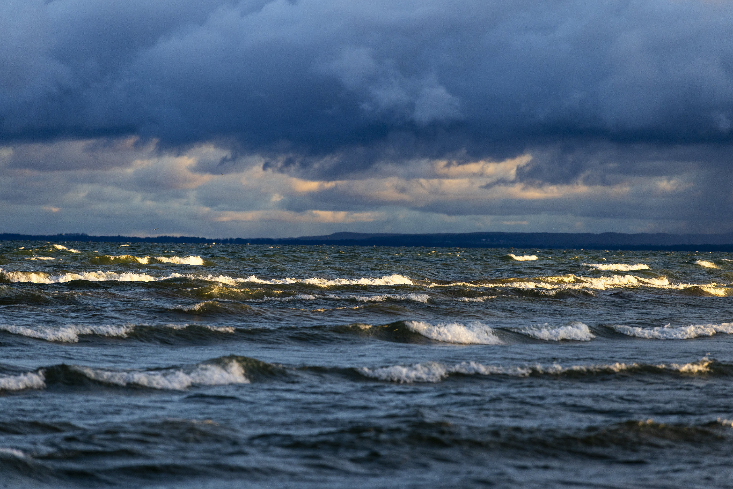 A cloudy sunrise drenches Lake Huron in dramatic lighting as whitecaps roll into the shore at Wasaga Beach.