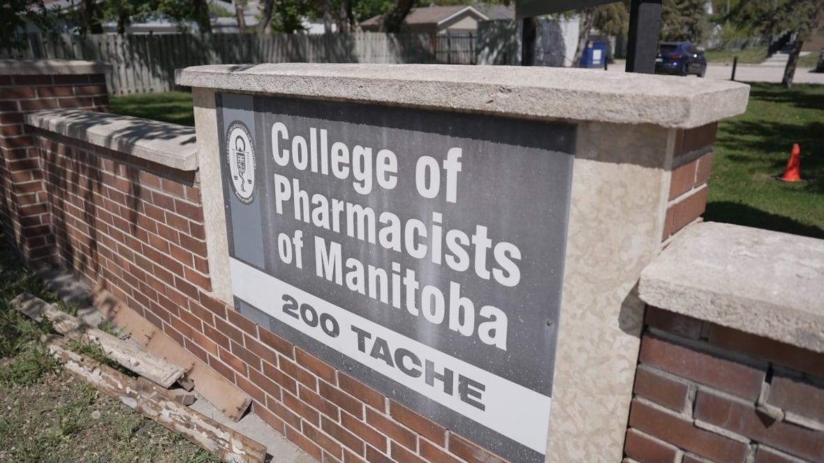 A brown brick fence in a yard has a sign showing the name of the College of Pharmacists of Manitoba written in white on a grey background.