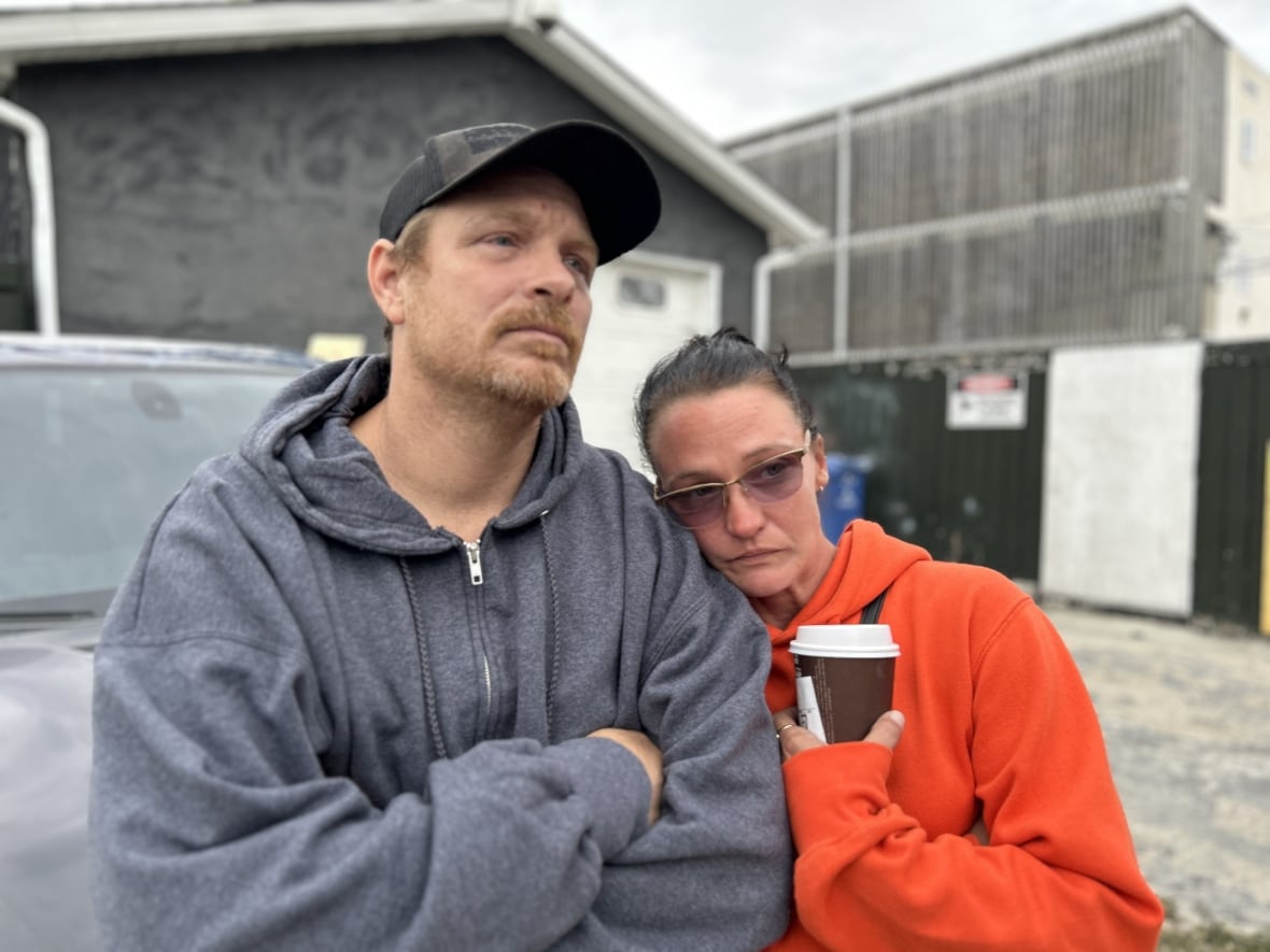 A man and a woman embrace while looking upset. 