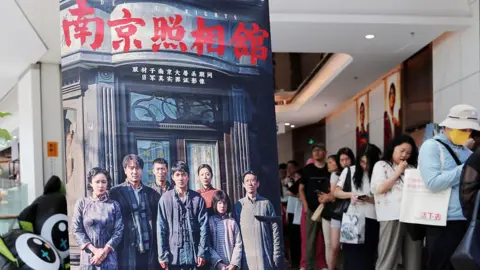 CFOTO/Future Publishing via Getty Images Movie fans queue by the promotional poster of the film "Dead To Rights" in the cinema