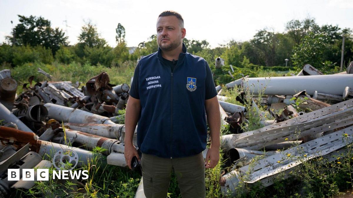 Dymtro Chubenko stands in front of a pile of Russian missile and drone parts