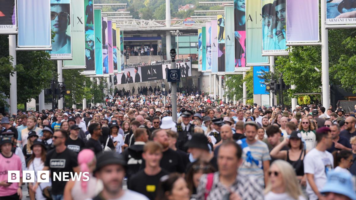Oasis fans, some wearing T-shirts featuring the band's name, on Wembley Way.