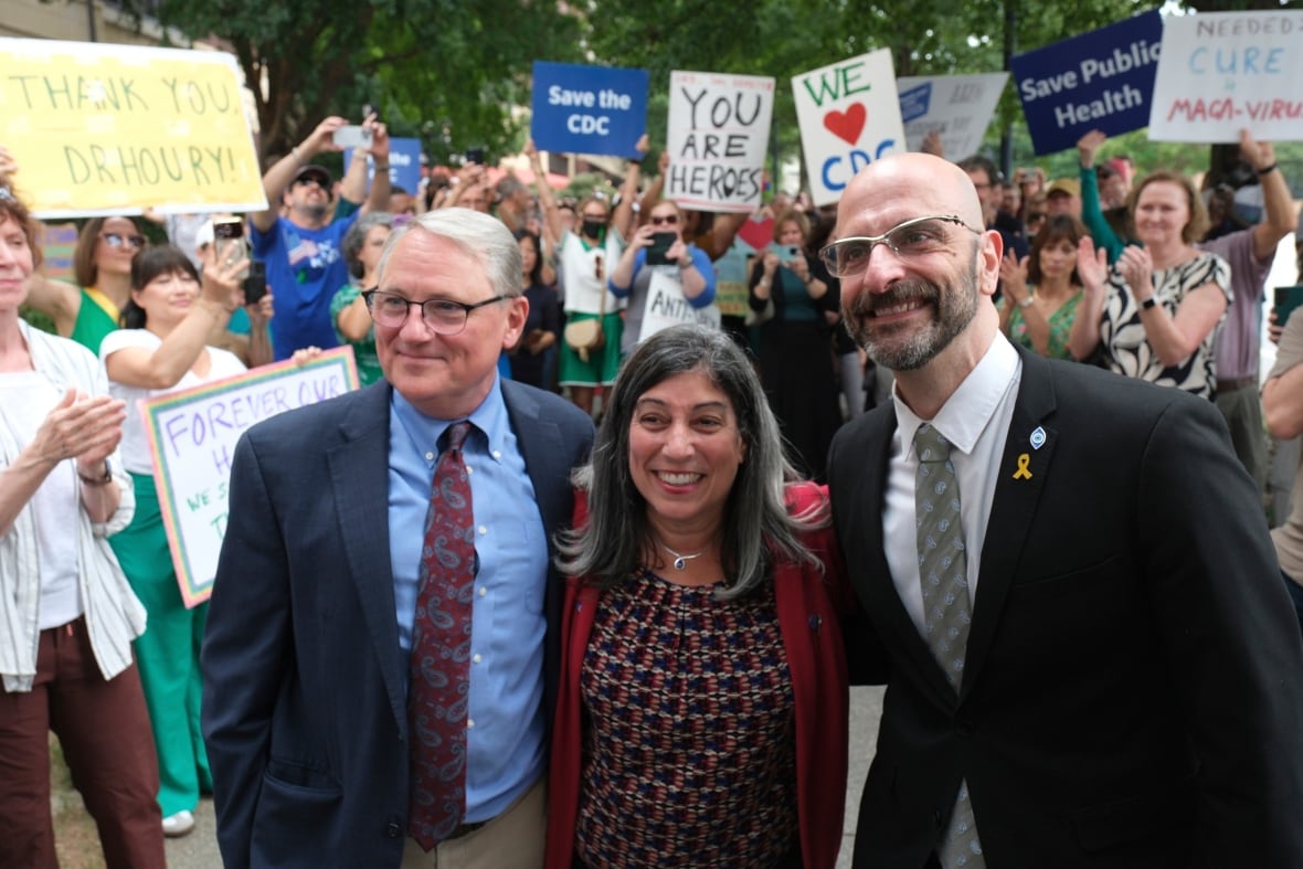 Three senior officials who resigned from the U.S. Centers for Disease Control and Prevention pose for a photo, in front of a crowd of supporters, at the Atlanta headquarters of the CDC.