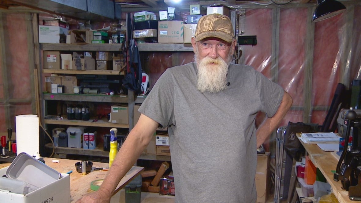 A man wears a baseball cap and gray t-shirt.