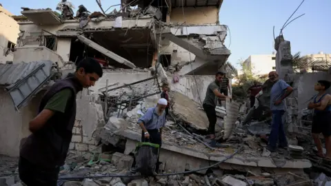 Reuters Palestinians inspect the site of an overnight Israeli strike on a house in Gaza City, 20 August 2025