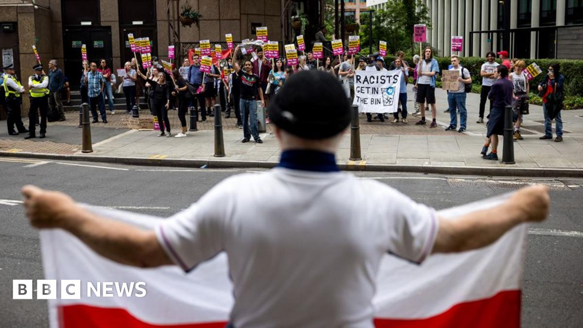 A man holds a flare during a protest outside The Bell Hotel on July 31, 2025 in Epping, England.