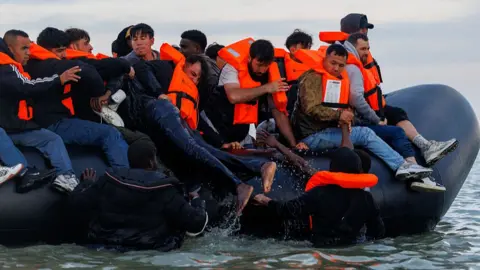 Getty Images People clambering onto a small boat in the Channel near France