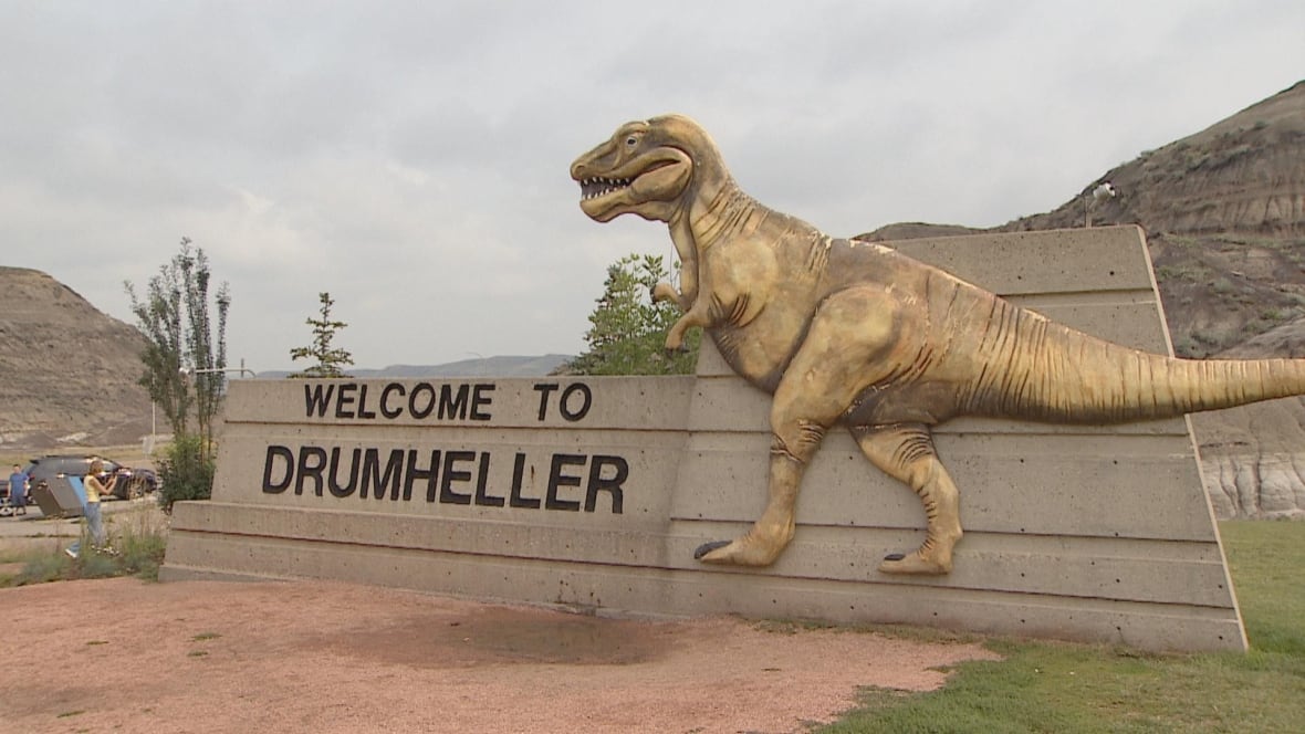 A dinosaur is pictured on a sign that reads Welcome to Drumheller.