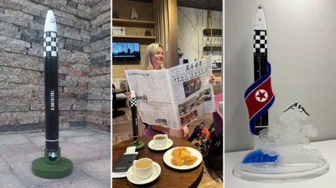 Anastasia Samsonova Three images: a North Korean missile model outdoors; tourist Anastasia in a café with a North Korean newspaper and a missile figurine, with coffee and pastries on the table; and the last image showing another missile figurine.