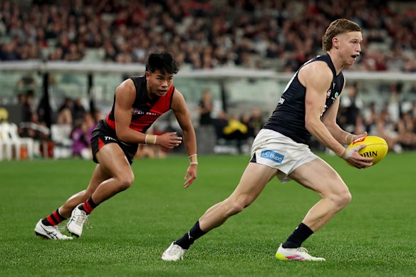 Flynn Young of the Blues runs with the ball under pressure from Jayden Nguyen of the Bombers.