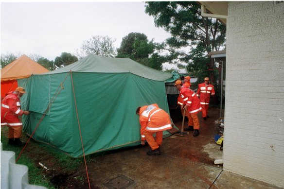 Emergency services personnel at the rear of a house during the investigation into the murders.
