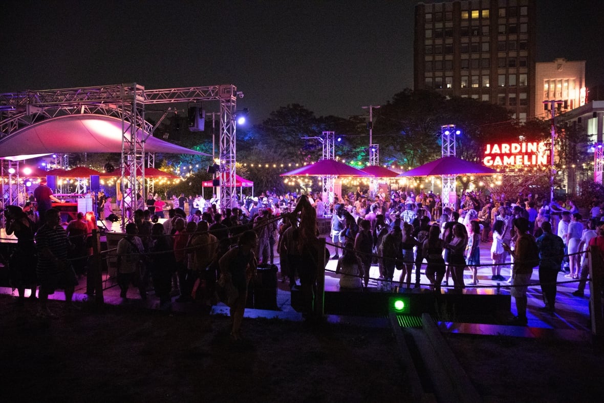 A crowd around a stage with a DJ