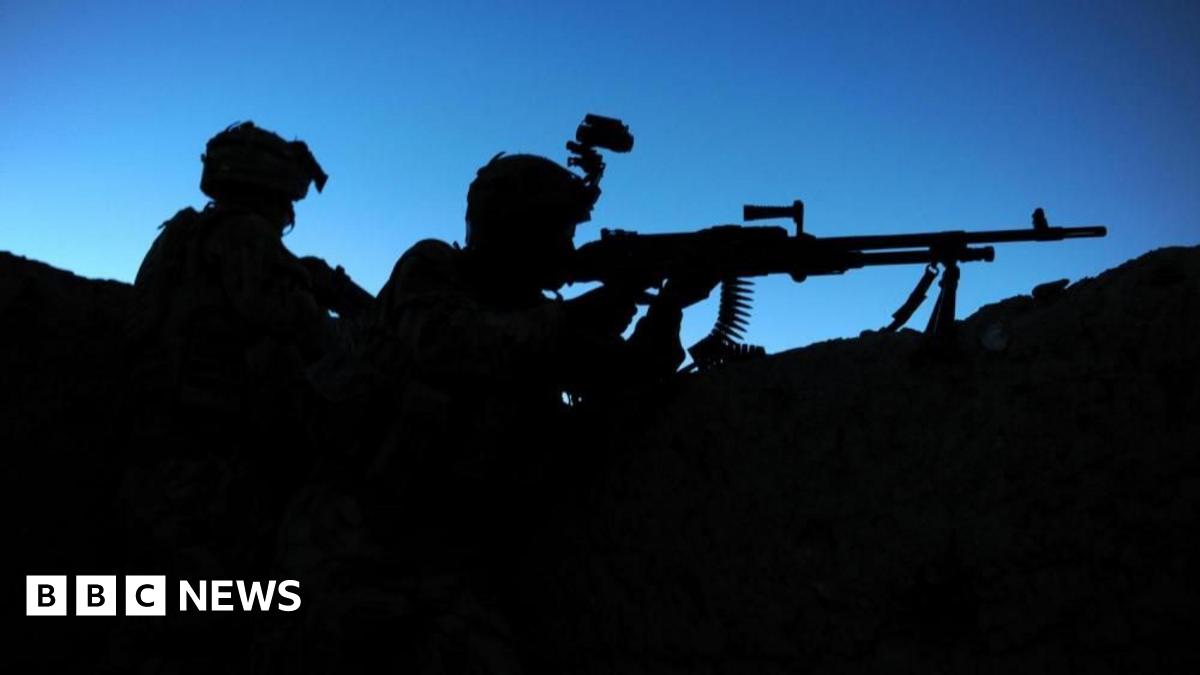 Two soldiers seen in silhouette against a blue sky