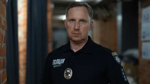 Lee Durant/BBC Police Colonel Serhii Bolvinov stands in uniform staring into the cameraman