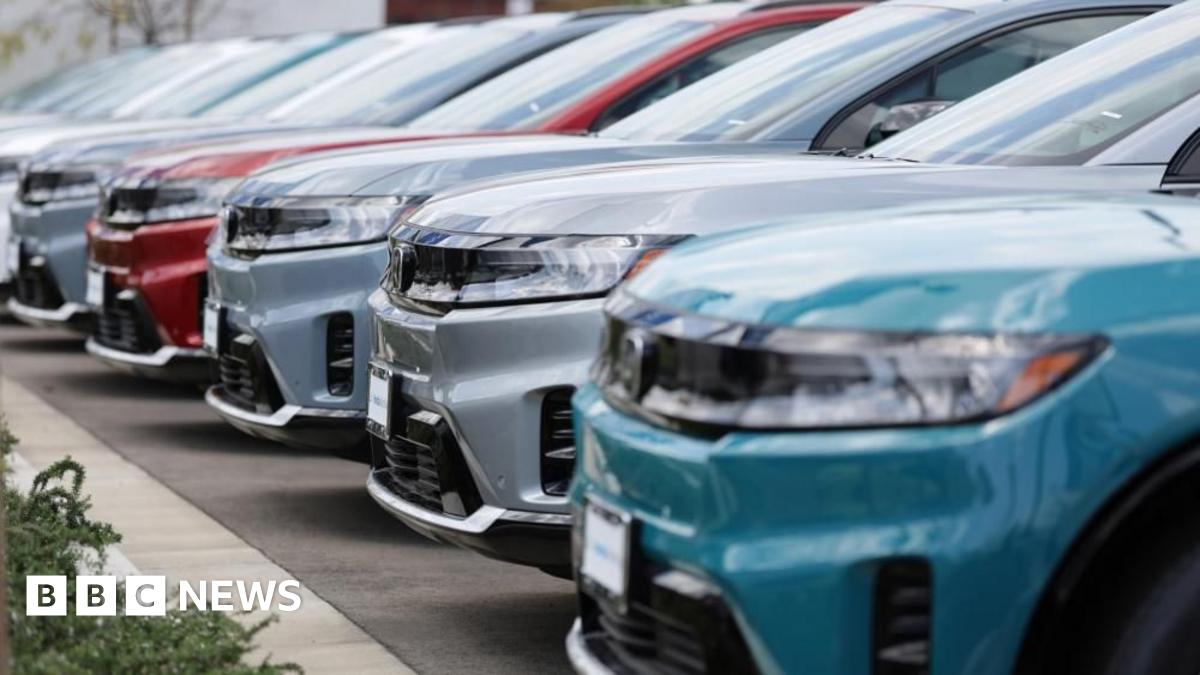 A row of shiny new SUVs in silver, red and blue sit parked in a car dealership.