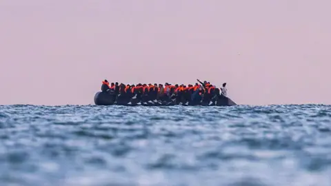 NurPhoto via Getty Images A side view of a small rubber boat filled with people wearing life jackets crosses the English Channel towards the UK.