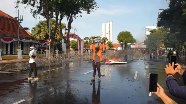 A protestor standing in the middle of a road holding up a banner