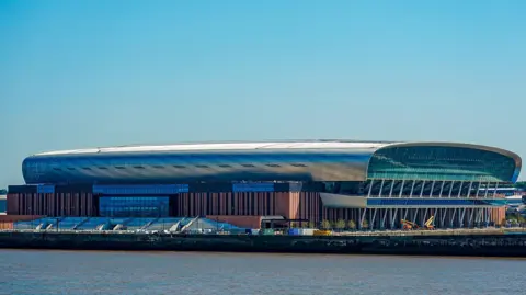 PA Media Image shows the Hill Dickinson Stadium, home to Everton FC. It is an oval-shaped stadium that sits on the Liverpool waterfront to the north of the city. 