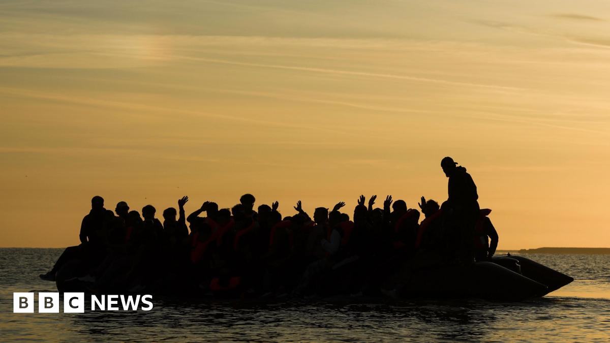A silhouette image of at least 20 people sitting on an inflatable dinghy at sea.