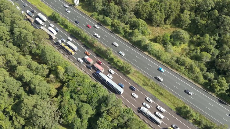 A traffic jam on highway surrounded by bush.