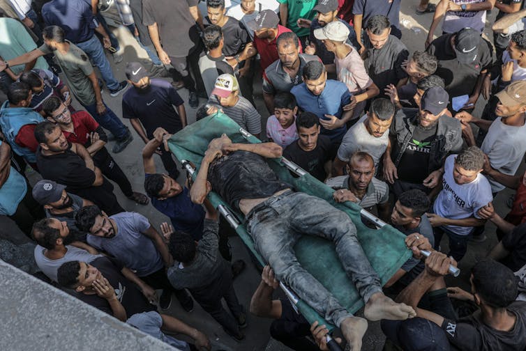 Palestinians carry the body of a young man killed by Israeli gunfire at an aid distribution point.