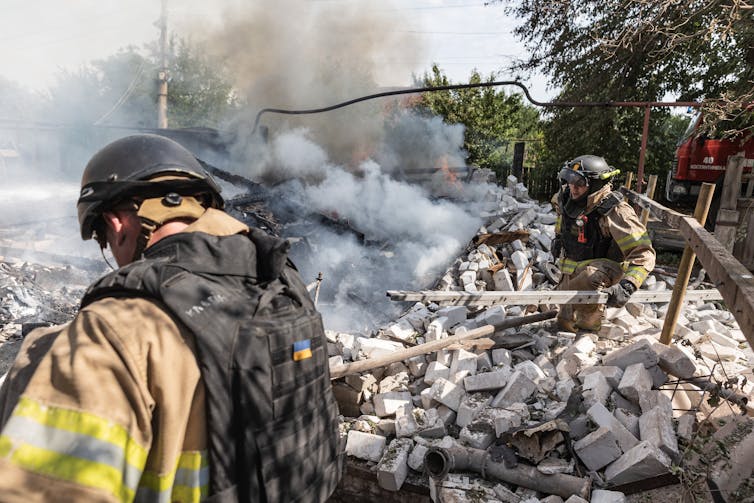 Firefighters wade through rubble.