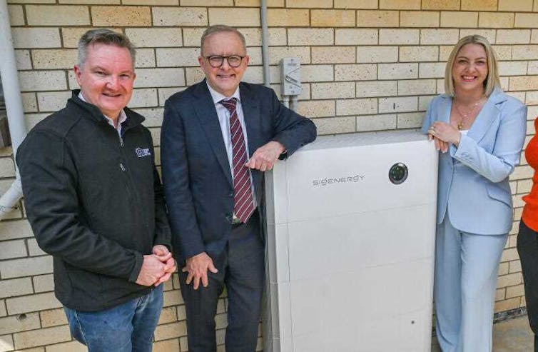 women and a woman stand next to a home solar battery.
