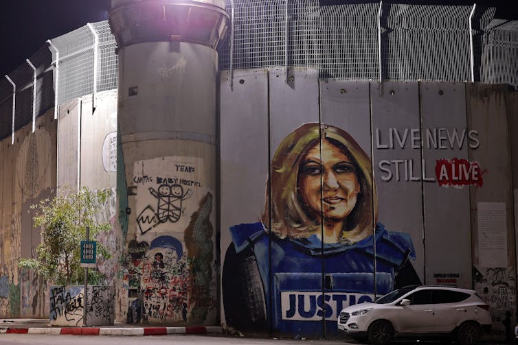 The image of a woman with a flak jacket with 'justice' written on it is seen on a wall