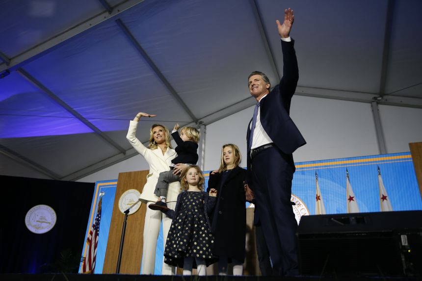 Newsom gestures to the crowd alongside his wife, Jennifer Siebel Newsom, and children on January 7, 2019, in Sacramento, California.