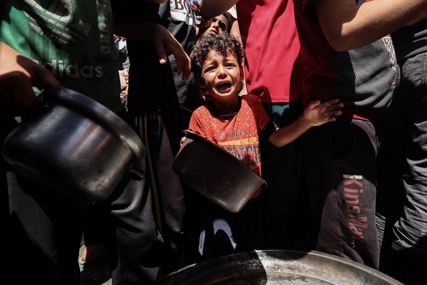 A child cries as Palestinians gather to receive a hot meal at a food distribution point in the Nuseirat camp for refugees in the central Gaza Strip on May 24.
