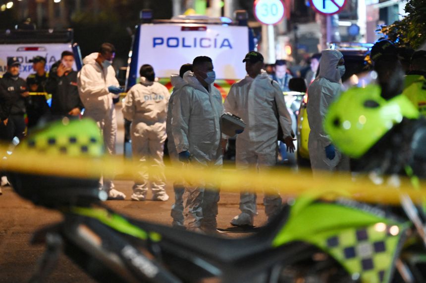 Forensic experts work at the scene where Uribe was shot in Bogota on June 7.