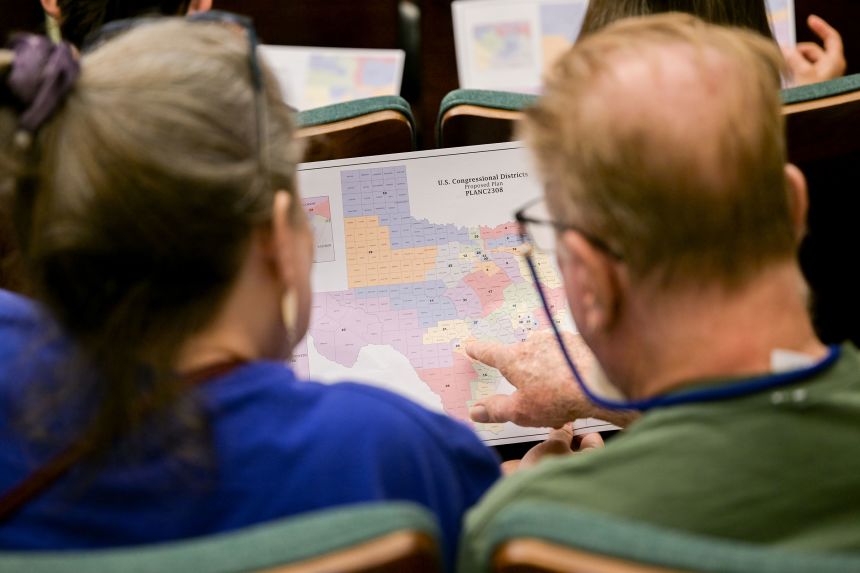 Attendees at an August 7 hearing by the Senate Special Committee on Congressional Redistricting in Austin, Texas, look at a map of the state.