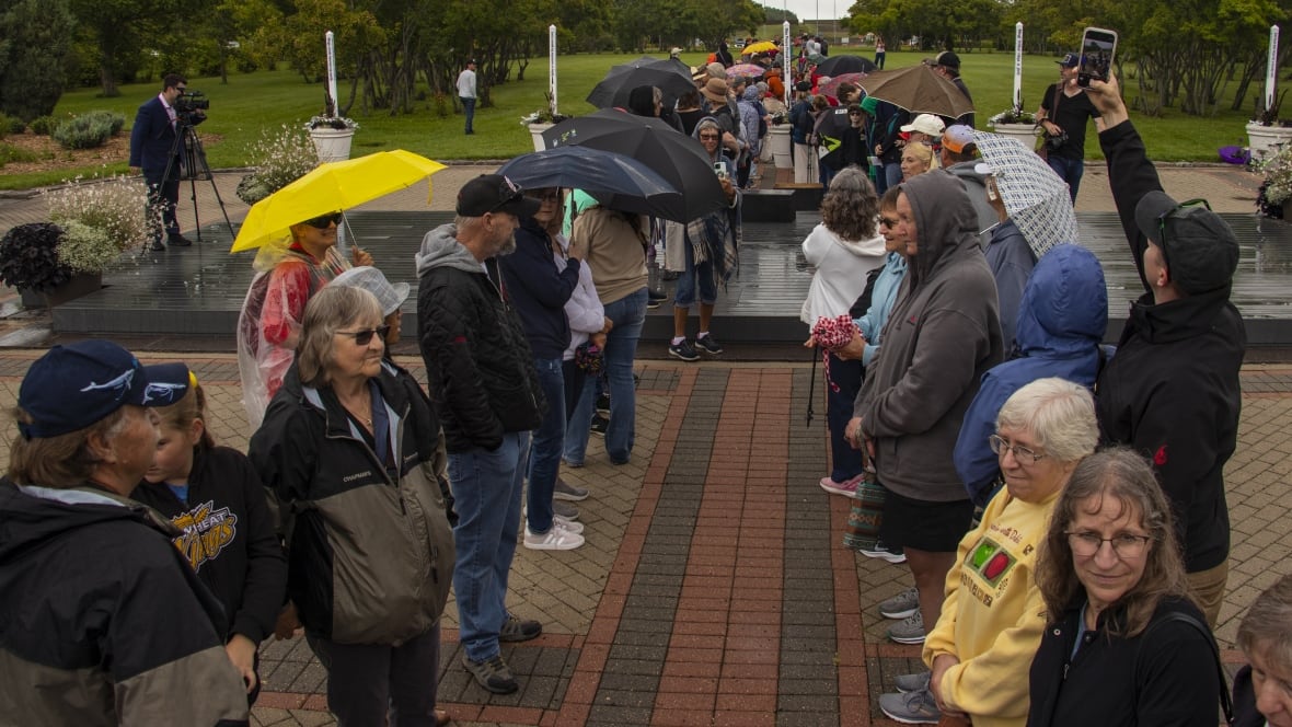 A line up of people on the left and on the right stand at the site of the International Peace Garden. 