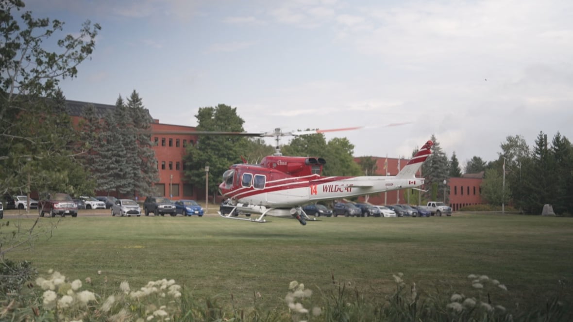 A helicopter takes flight from a lawn.