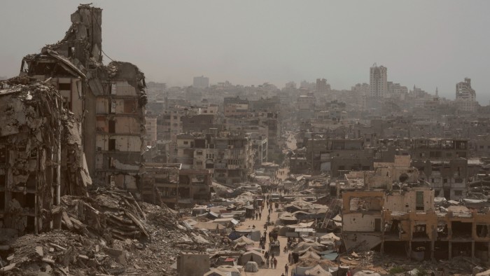 People walk down a street surrounded by buildings destroyed by Israeli bombardments in the Gaza Strip